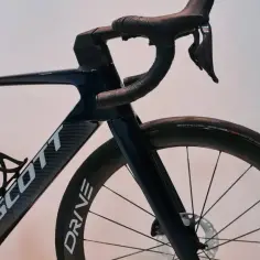 Ciemnoniebieski rower Scott z karbonową ramą i kierownicą. Widoczny mostek, koło z oponą Schwalbe Pro One i hamulec tarczowy.