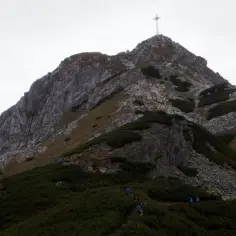 Giewont dla początkujących. Grupa turystów wchodzi na szlak, widoczny krzyż na szczycie.