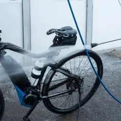 Elektryczny rower jest myty na myjni. Woda spływa po ramie, baterii i kołach.