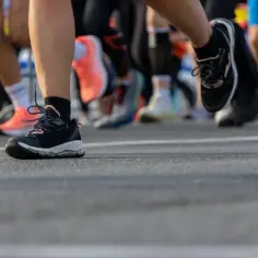 Uczestnicy biegu, czyli joggingu, w sportowych butach na asfalcie.