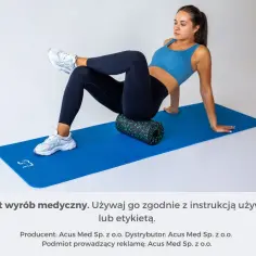 Kobieta wykonuje ćwiczenia na mięsień gruszkowaty, używając rollera do masażu na macie.
