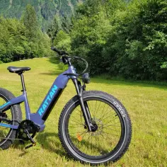 Fioletowy rower elektryczny RATTAN Sequoia na tle zielonych wzgórz. Idealny do odkrywania nowych szlaków, zgodnie z przepisami ruchu drogowego.