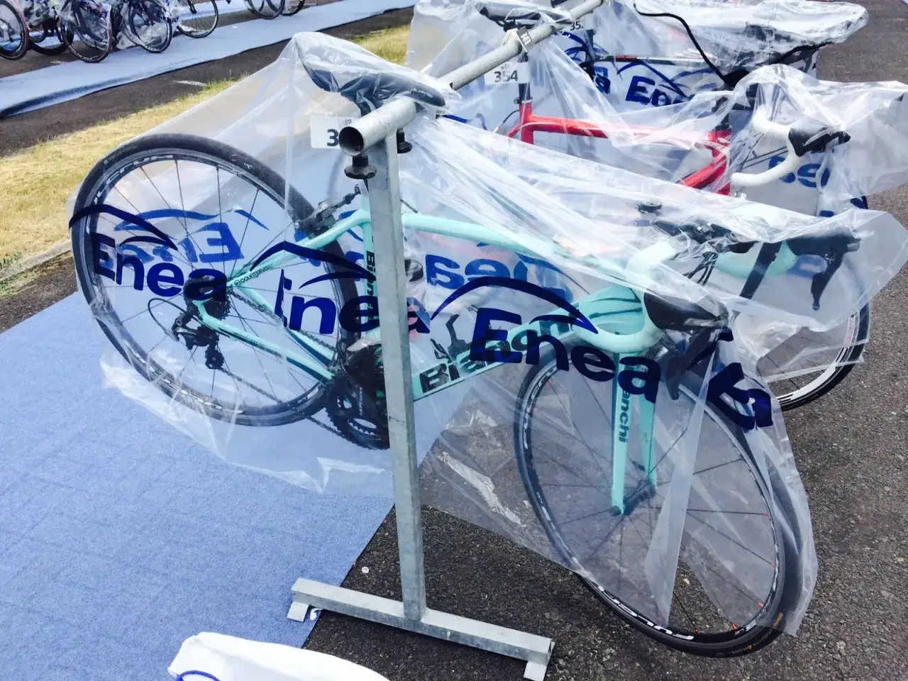 Rowery gotowe do startu w triathlonie olimpijskim, każdy w ochronnej folii.