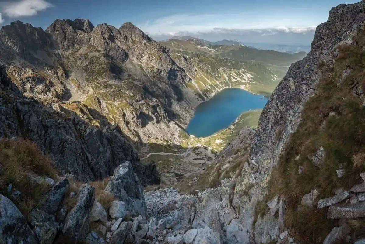 Widok z Orlej Perci na Morskie Oko. Trasa wije się wśród skalistych zboczy, oferując zapierające dech w piersiach krajobrazy Tatr.